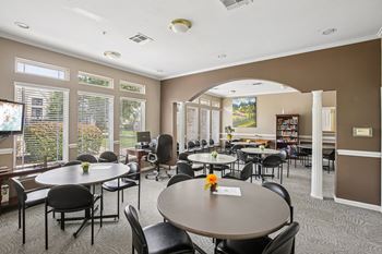 A room with tables and chairs and a vase of flowers on the table.